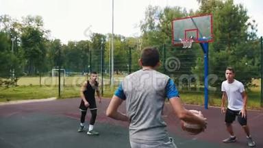 年轻的运动员和朋友一起在球场上打篮球，运球和丢篮球